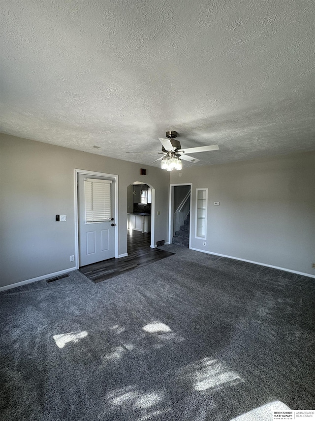 unfurnished living room with a textured ceiling, ceiling fan, and dark colored carpet