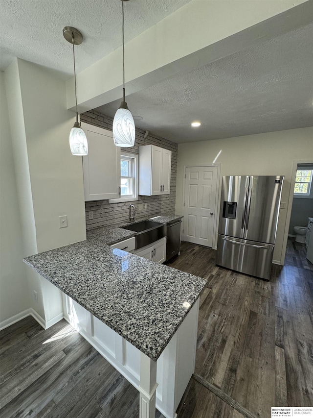 kitchen featuring white cabinetry, pendant lighting, kitchen peninsula, and appliances with stainless steel finishes