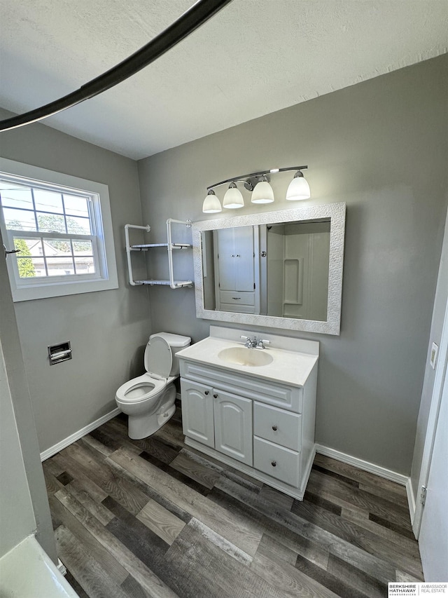 bathroom with wood-type flooring, toilet, vanity, and a textured ceiling