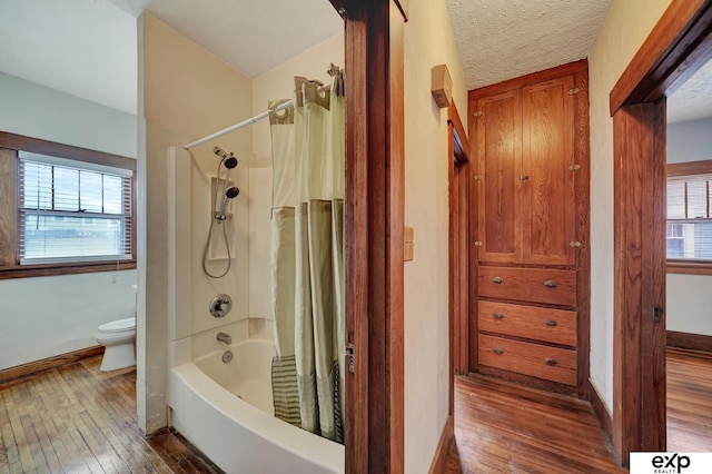 bathroom with wood-type flooring, toilet, a textured ceiling, and shower / bath combo with shower curtain