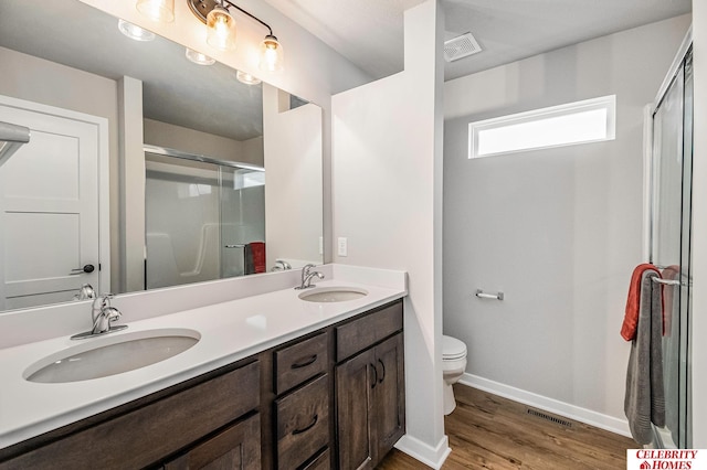 bathroom with an enclosed shower, hardwood / wood-style floors, vanity, and toilet