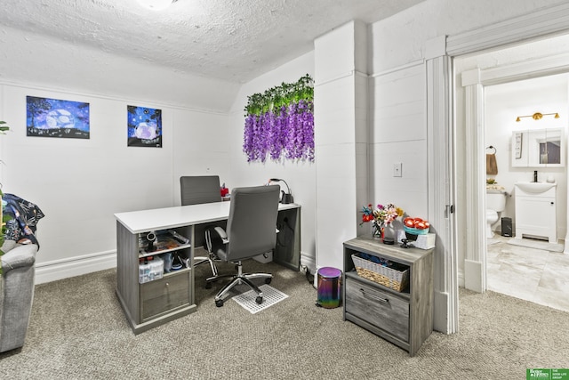 office area featuring lofted ceiling, carpet flooring, sink, and a textured ceiling