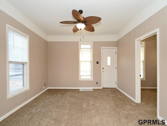 carpeted entryway with ornamental molding and ceiling fan