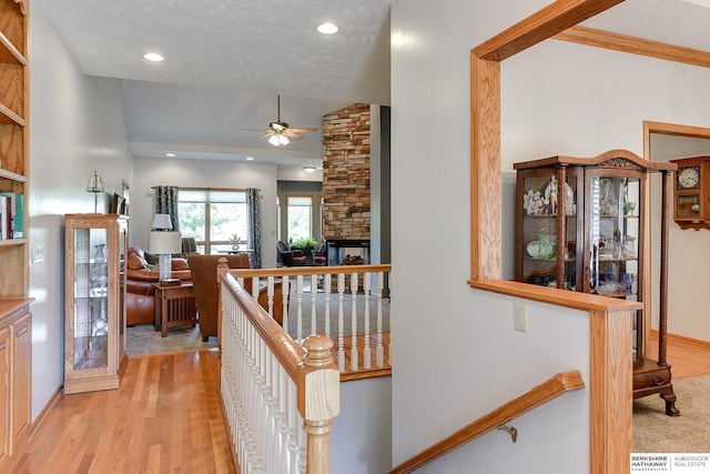 corridor with vaulted ceiling, light hardwood / wood-style floors, and a textured ceiling