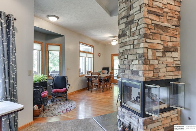 living room with hardwood / wood-style flooring, ceiling fan, a fireplace, and a textured ceiling