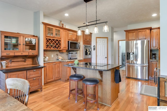 kitchen featuring decorative backsplash, stainless steel appliances, a center island, and dark stone counters