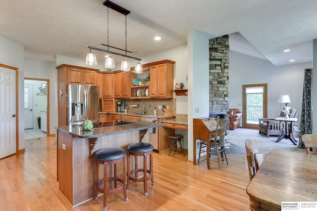 kitchen featuring sink, stainless steel appliances, a kitchen breakfast bar, decorative light fixtures, and light wood-type flooring