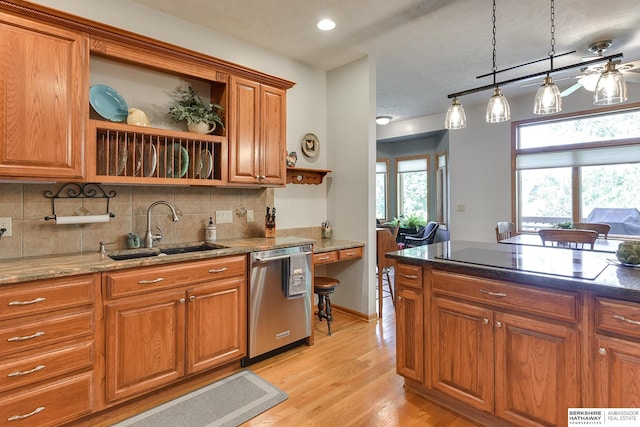 kitchen with sink, black electric cooktop, dishwasher, pendant lighting, and dark stone counters