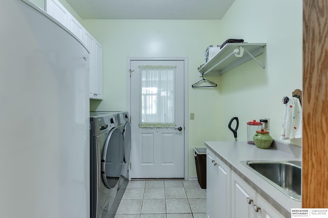 laundry room with sink, cabinets, a textured ceiling, washer and dryer, and light tile patterned floors