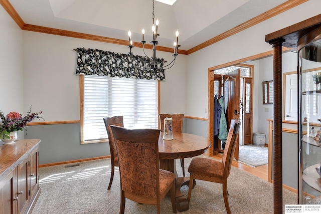 dining space featuring ornamental molding, light carpet, an inviting chandelier, and a tray ceiling