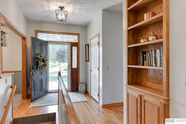 foyer entrance featuring a textured ceiling and light wood-type flooring