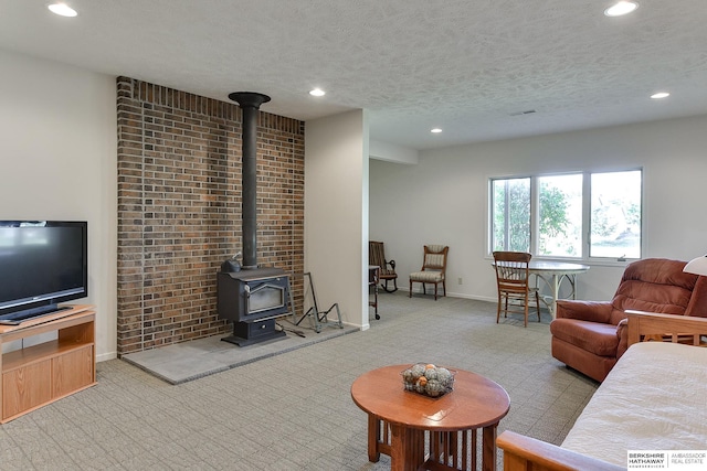 living room with light colored carpet, a textured ceiling, and a wood stove