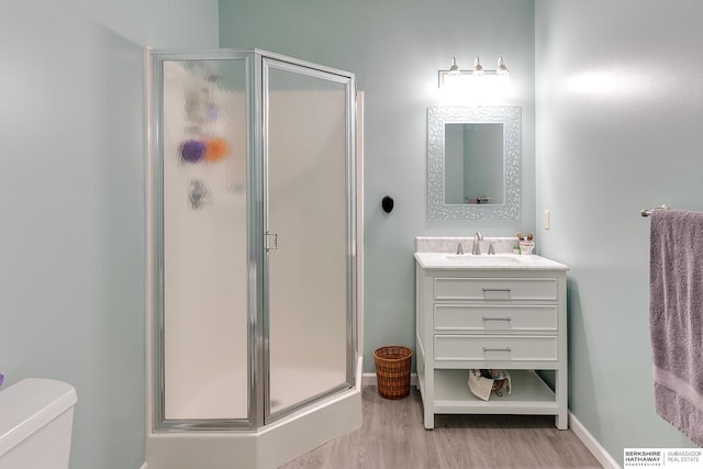 bathroom with vanity, toilet, a shower with shower door, and wood-type flooring