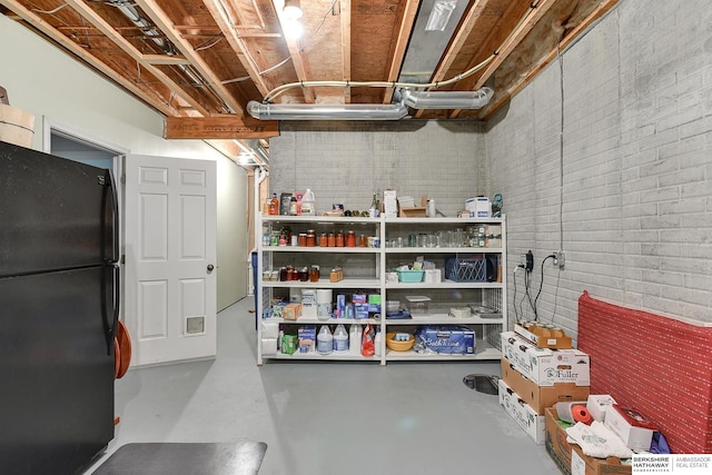 basement with brick wall and black fridge