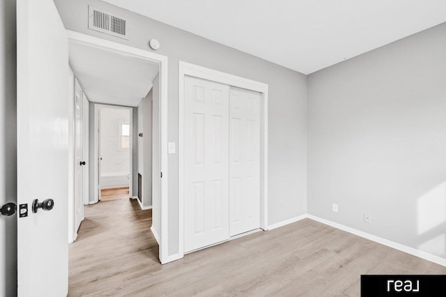 unfurnished bedroom with a closet and light wood-type flooring