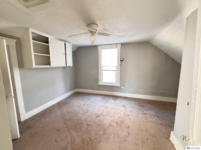 bonus room with carpet, lofted ceiling, a ceiling fan, a textured ceiling, and baseboards