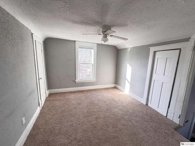 carpeted spare room with lofted ceiling, a ceiling fan, a textured ceiling, and a textured wall