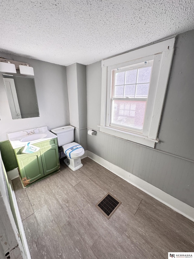 bathroom with visible vents, wainscoting, toilet, wood finished floors, and vanity