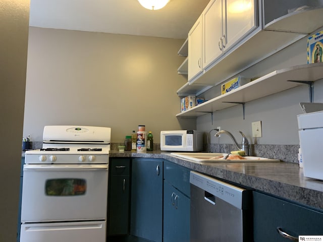 kitchen with white appliances, blue cabinetry, sink, and white cabinets