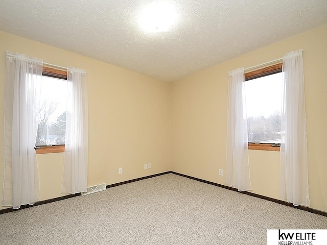 carpeted empty room featuring a textured ceiling