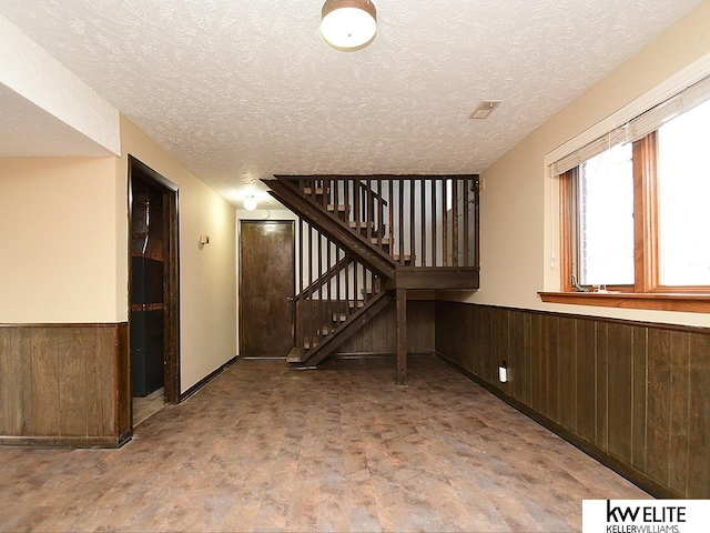 interior space featuring a textured ceiling and wood walls