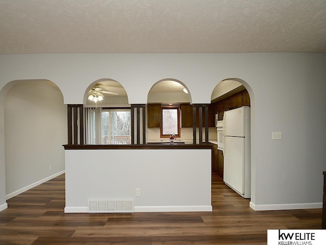 kitchen featuring dark hardwood / wood-style floors, white fridge, a kitchen island with sink, dark brown cabinets, and a textured ceiling