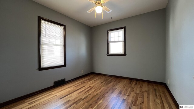 unfurnished room featuring light wood-style floors, baseboards, visible vents, and a ceiling fan