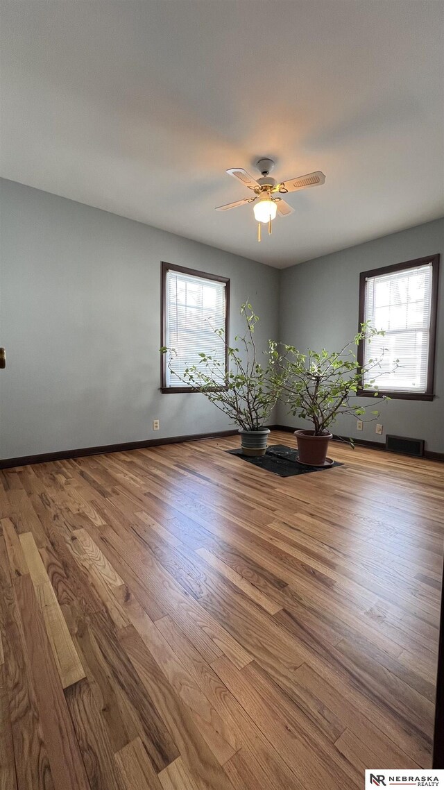 unfurnished room featuring a ceiling fan, visible vents, baseboards, and wood finished floors