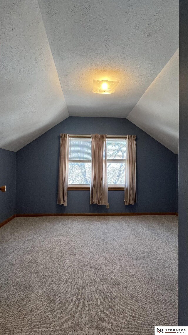 bonus room featuring vaulted ceiling, a textured ceiling, carpet, and baseboards