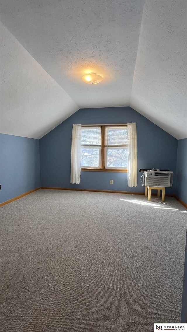 additional living space featuring carpet floors, lofted ceiling, a textured ceiling, and baseboards