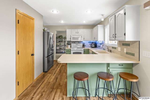 kitchen featuring white appliances, a kitchen breakfast bar, and white cabinets