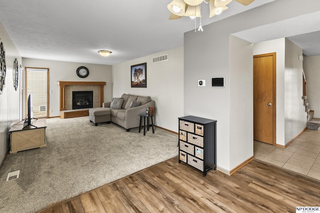 living room featuring ceiling fan, wood-type flooring, and a tile fireplace