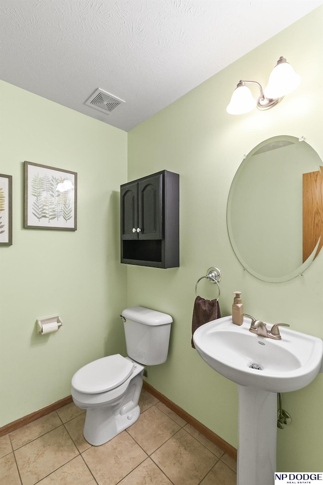 bathroom featuring tile patterned flooring, a textured ceiling, and toilet