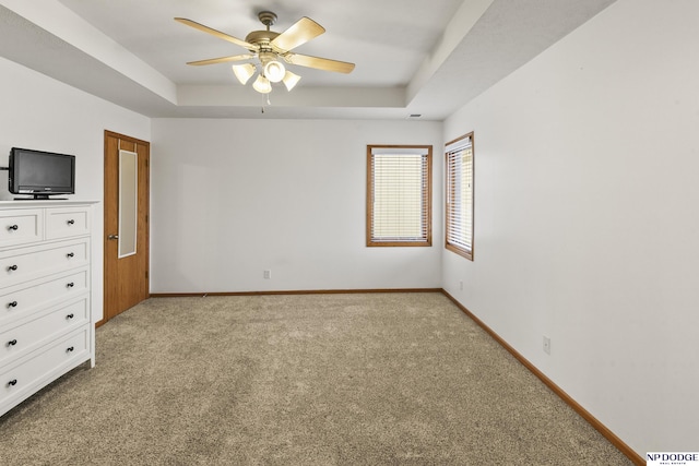 unfurnished bedroom with ceiling fan, light colored carpet, and a raised ceiling