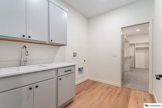 laundry area with sink, cabinets, hookup for a washing machine, electric dryer hookup, and light wood-type flooring