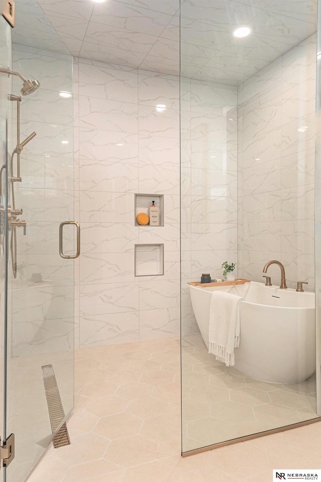 bathroom with shower with separate bathtub and tile walls