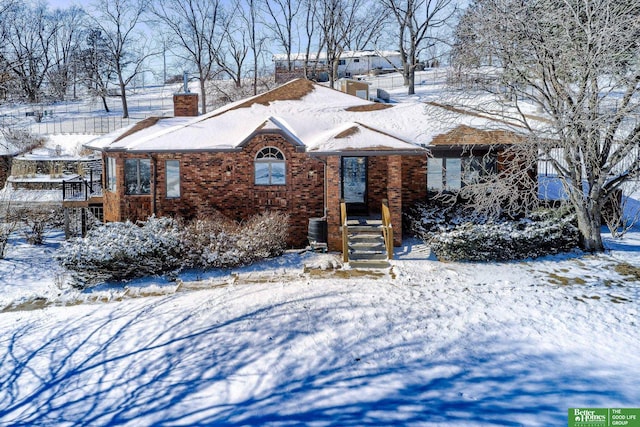 view of front of house with brick siding, a chimney, and central air condition unit