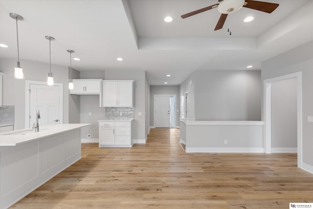 kitchen with a sink, light countertops, a raised ceiling, and white cabinetry