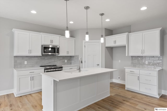 kitchen with a sink, light countertops, appliances with stainless steel finishes, and white cabinets