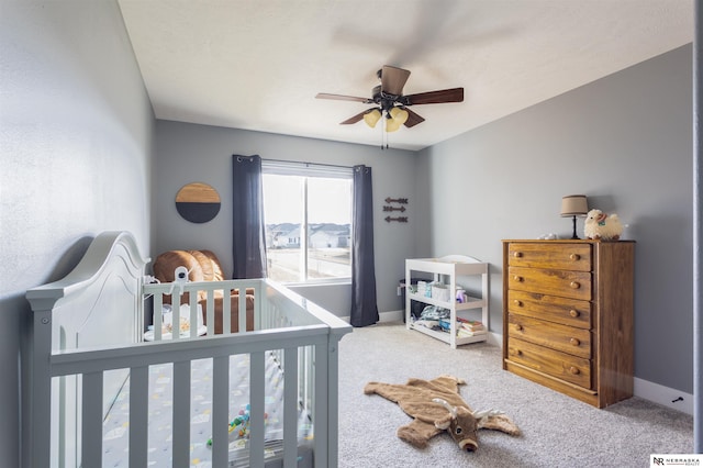 carpeted bedroom with ceiling fan and a crib