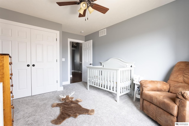 bedroom featuring ceiling fan, carpet flooring, a closet, and a crib