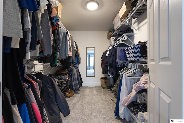 walk in closet with light carpet