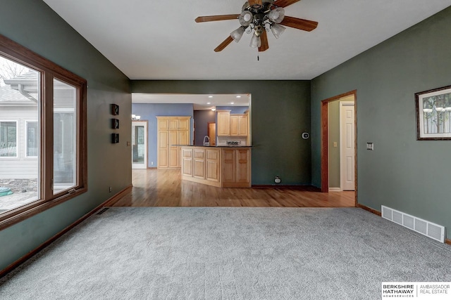 unfurnished living room with ceiling fan and light carpet