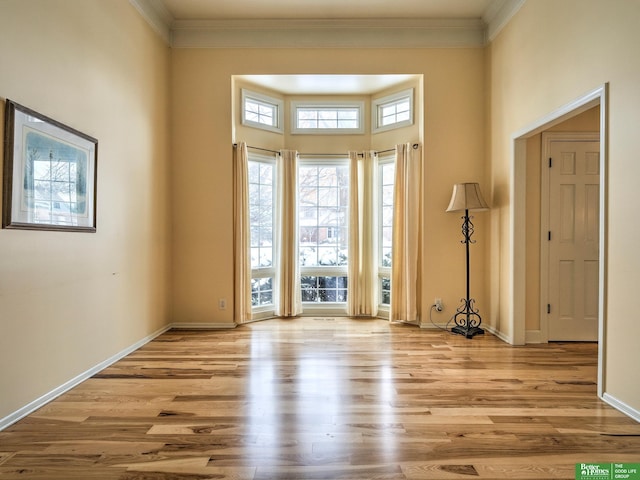 entryway with light wood finished floors, baseboards, and ornamental molding