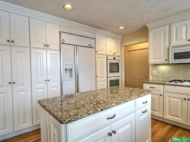 kitchen with light stone counters, white appliances, white cabinets, and light wood-style floors