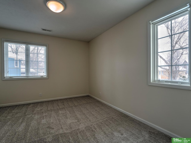 empty room featuring carpet floors, visible vents, and baseboards