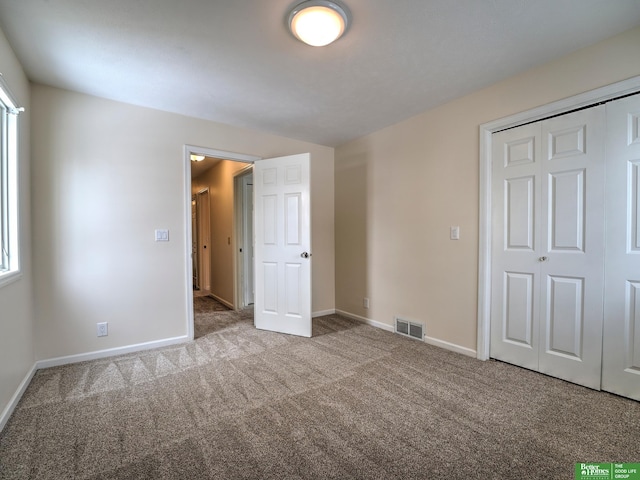 unfurnished bedroom with carpet floors, a closet, visible vents, and baseboards