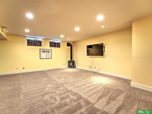 finished basement featuring baseboards, carpet, a wood stove, and recessed lighting