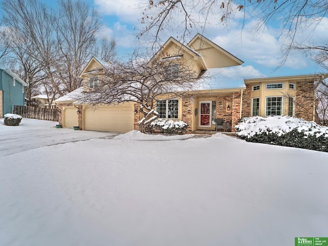 view of front of house featuring a garage, brick siding, and fence