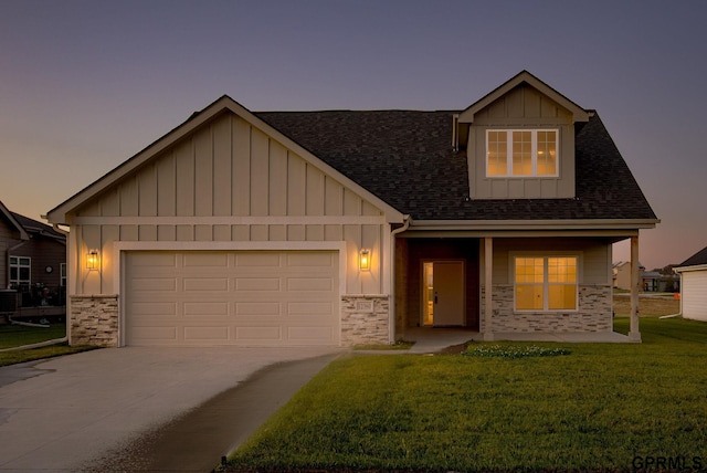 craftsman-style home featuring a garage, a yard, covered porch, and central air condition unit